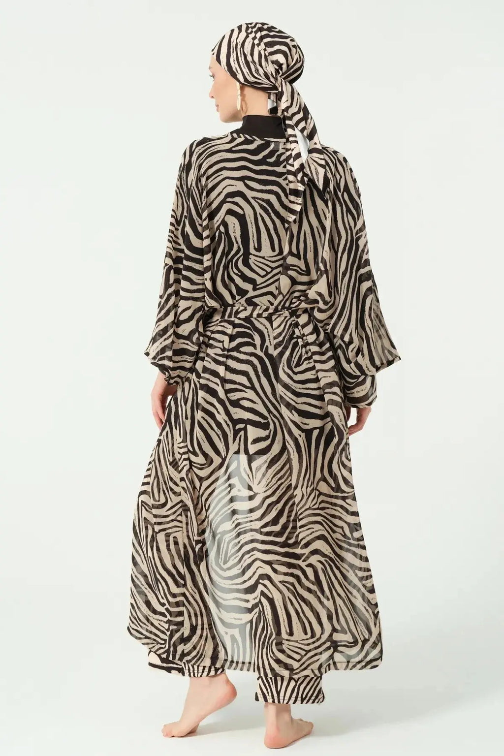 Model wearing zebra print sheer kimono over black modest swimwear, back view.