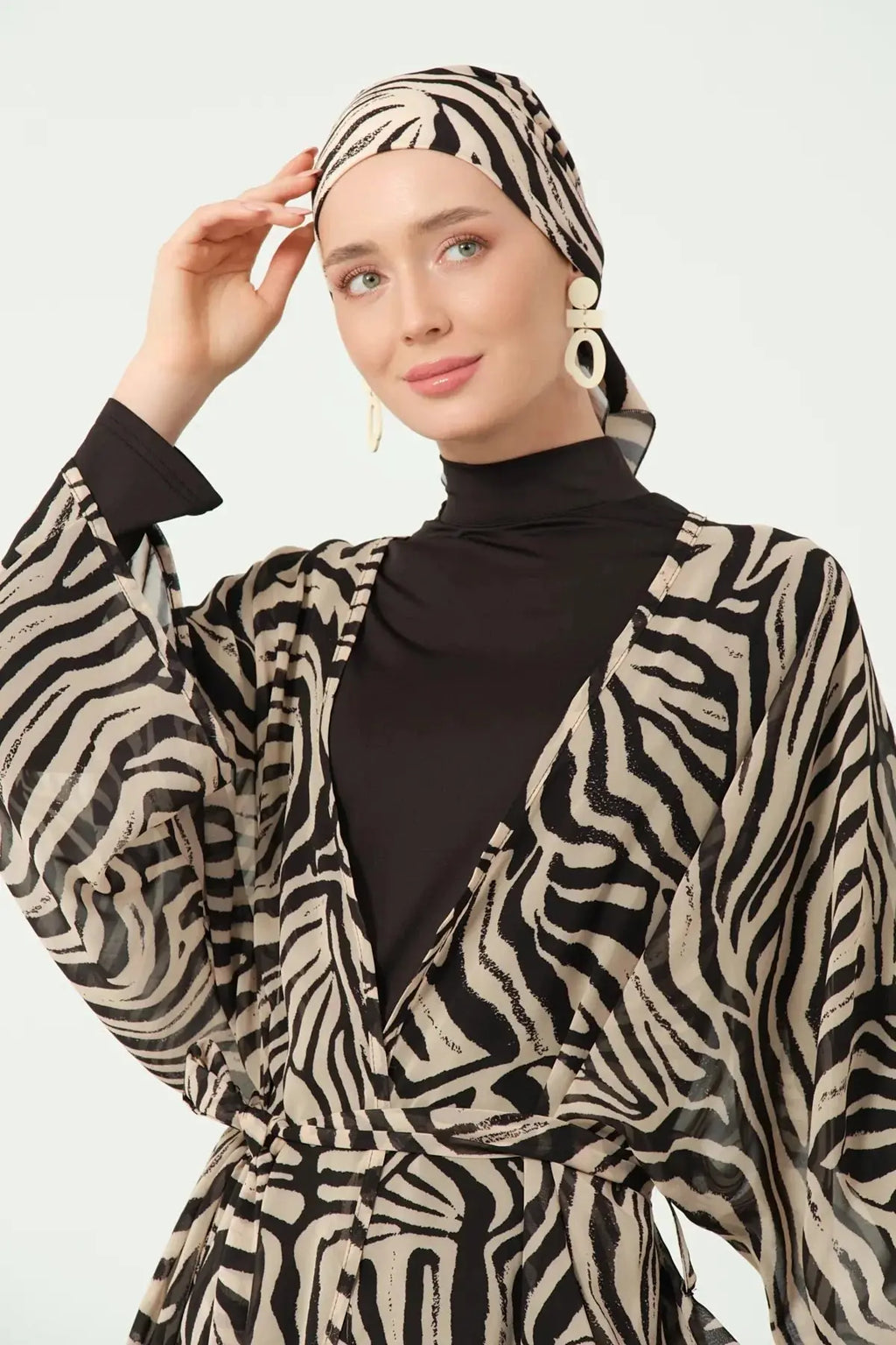 Model adjusting zebra print head covering with kimono and black swimwear.