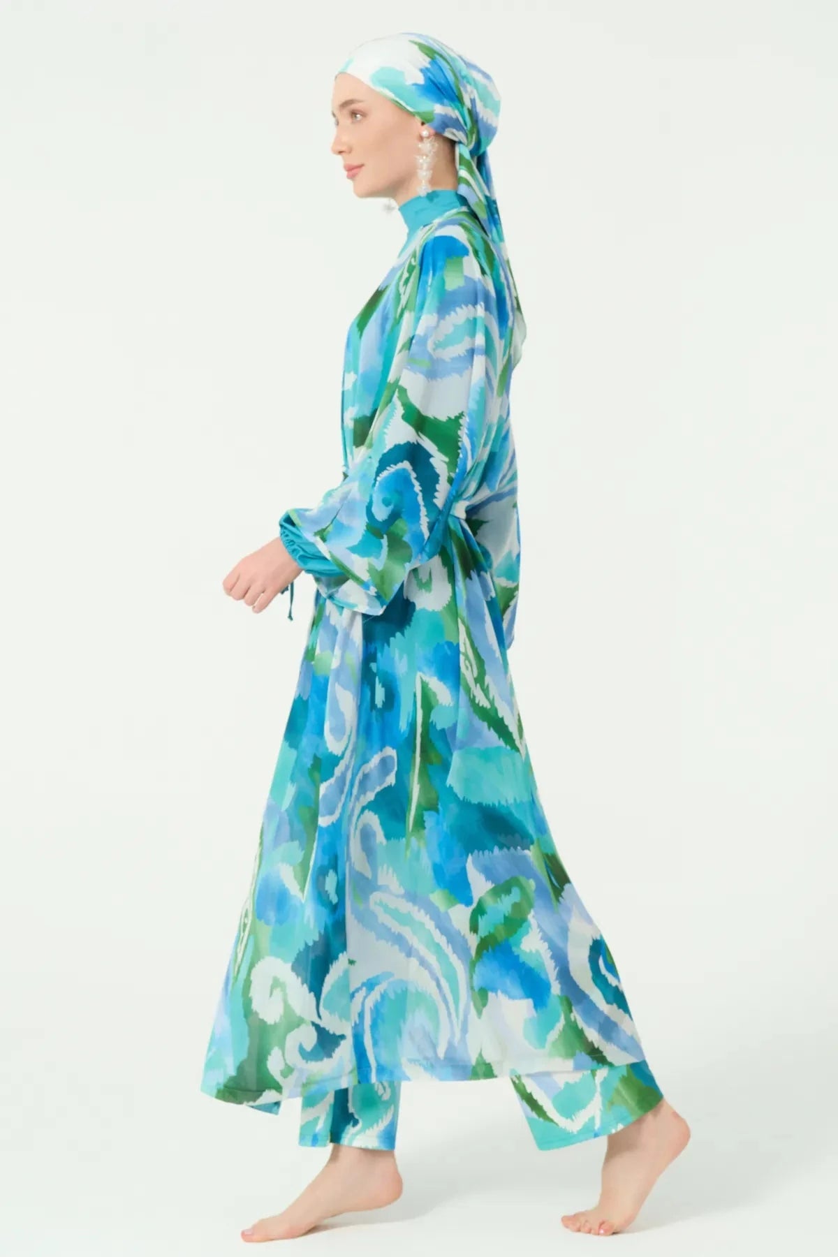 Side view of model walking in patterned modest kimono and head covering.