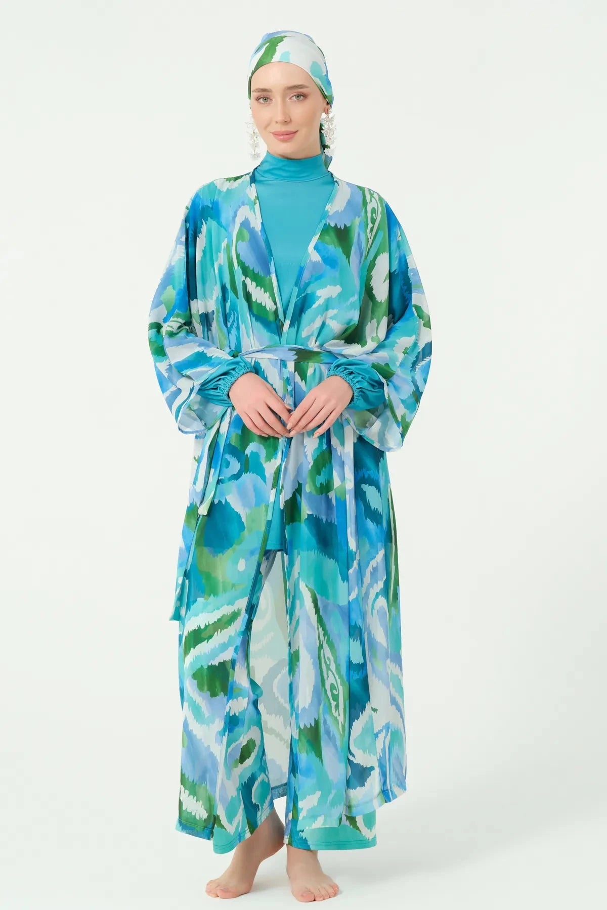 Front view of model in patterned kimono with belt, hands clasped.