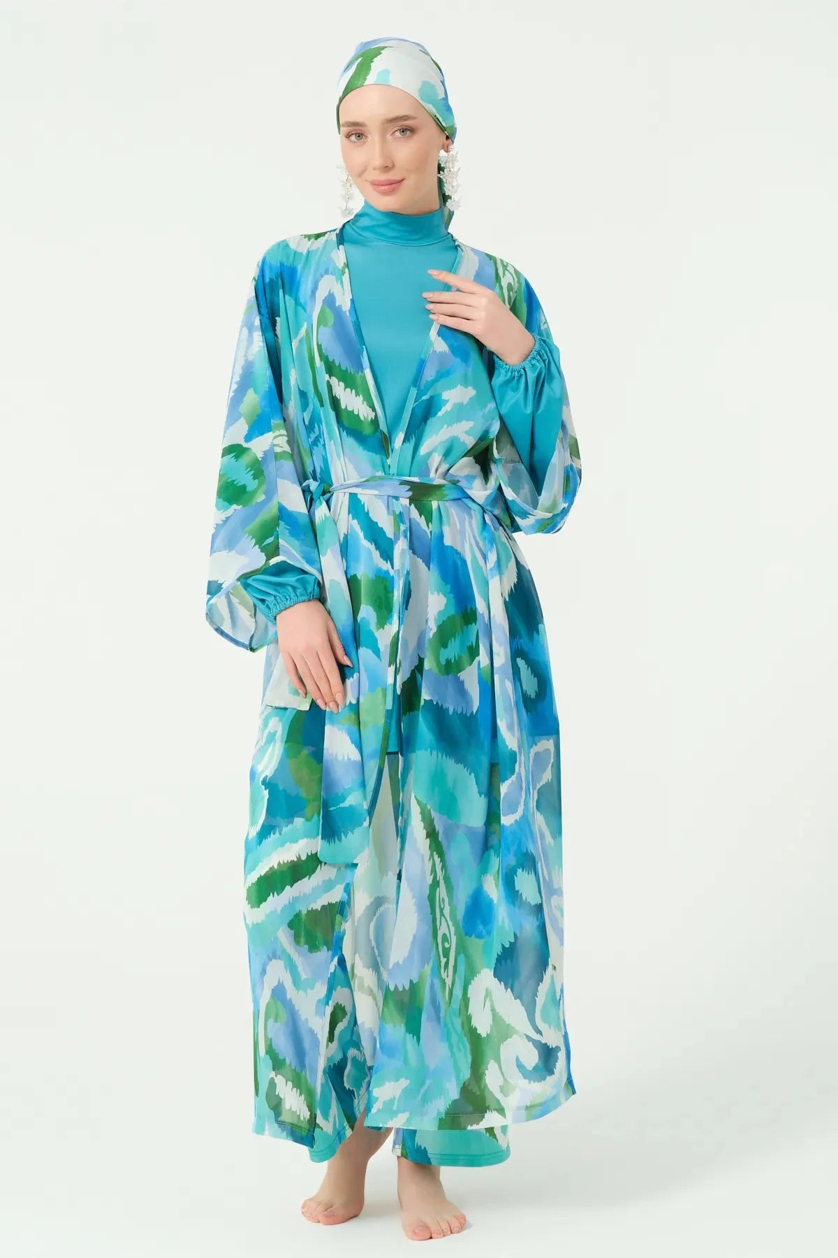 Model standing in blue and green patterned kimono with matching head covering.