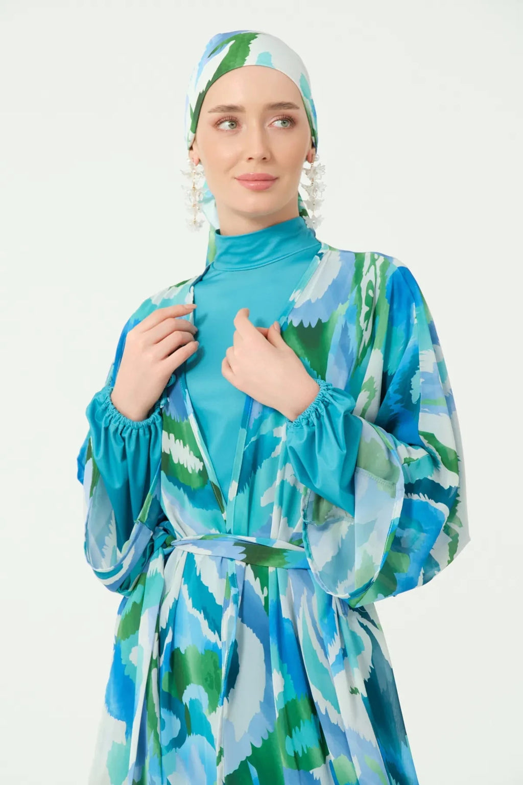 Close-up of blue and green patterned kimono with belt and head covering.