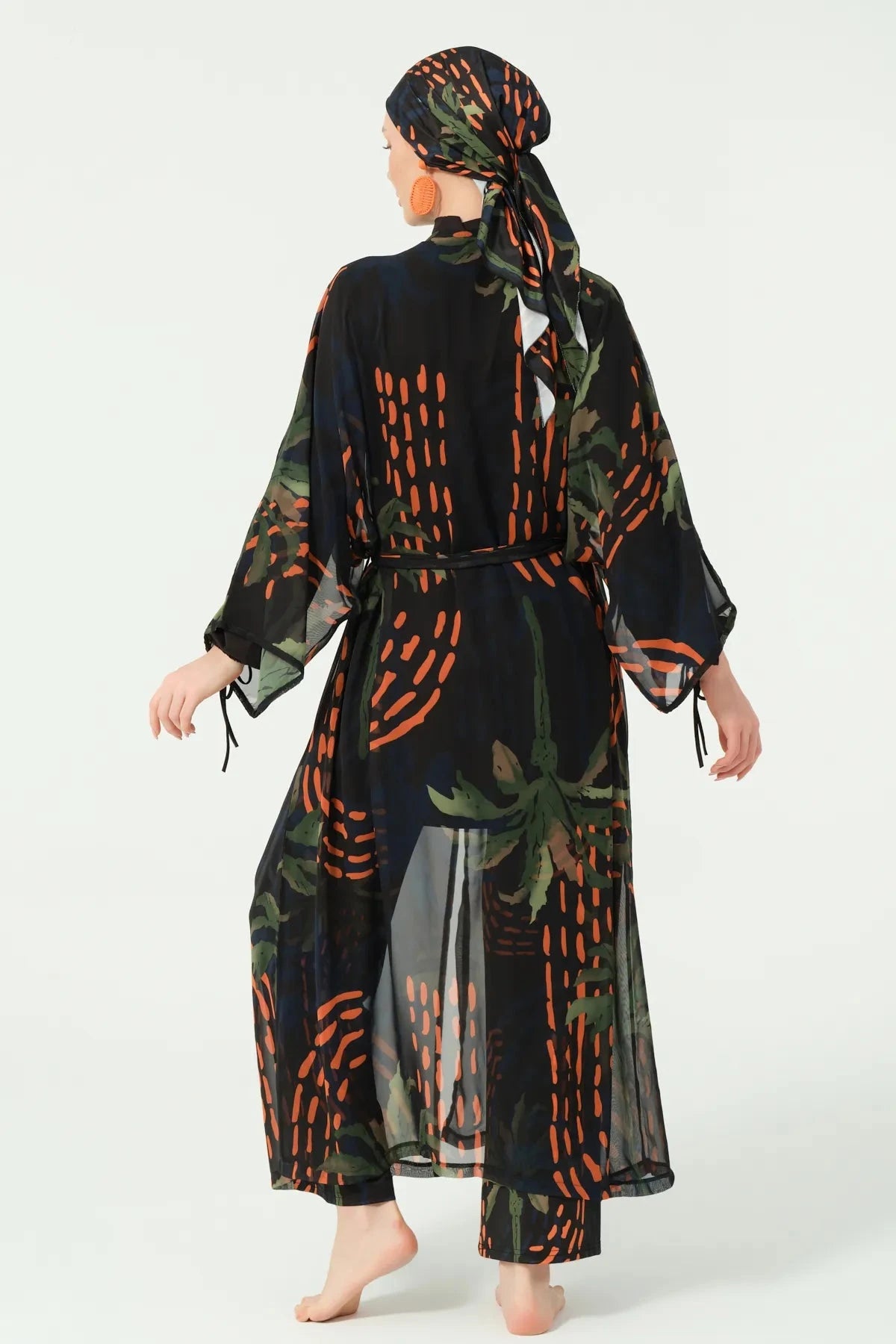 Woman in dark patterned kimono and head covering, back view.