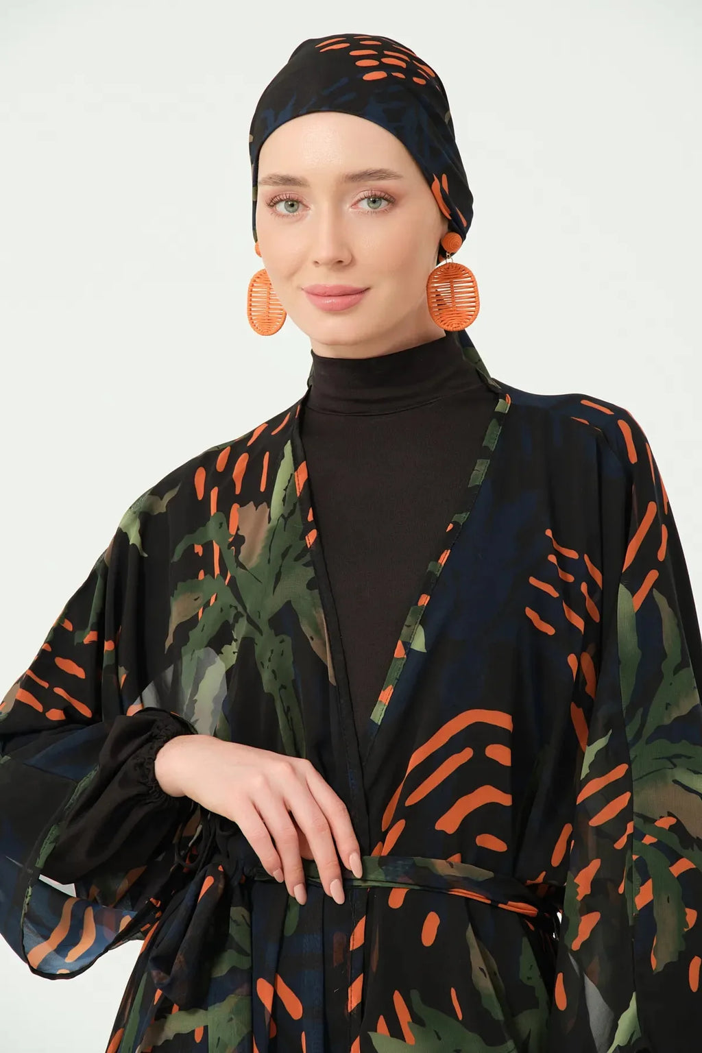 Close-up of patterned kimono and black modest swimwear with head covering.