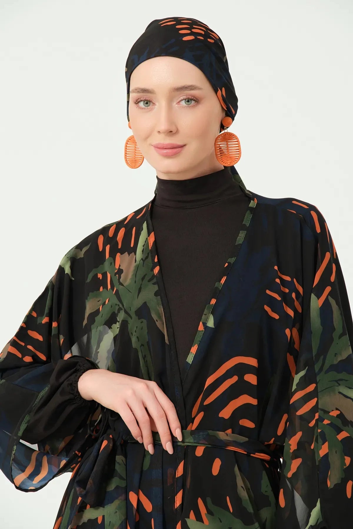 Close-up of patterned kimono and black modest swimwear with head covering.