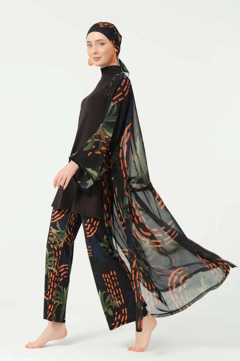 Woman walking in flowing dark patterned kimono and modest swimwear.