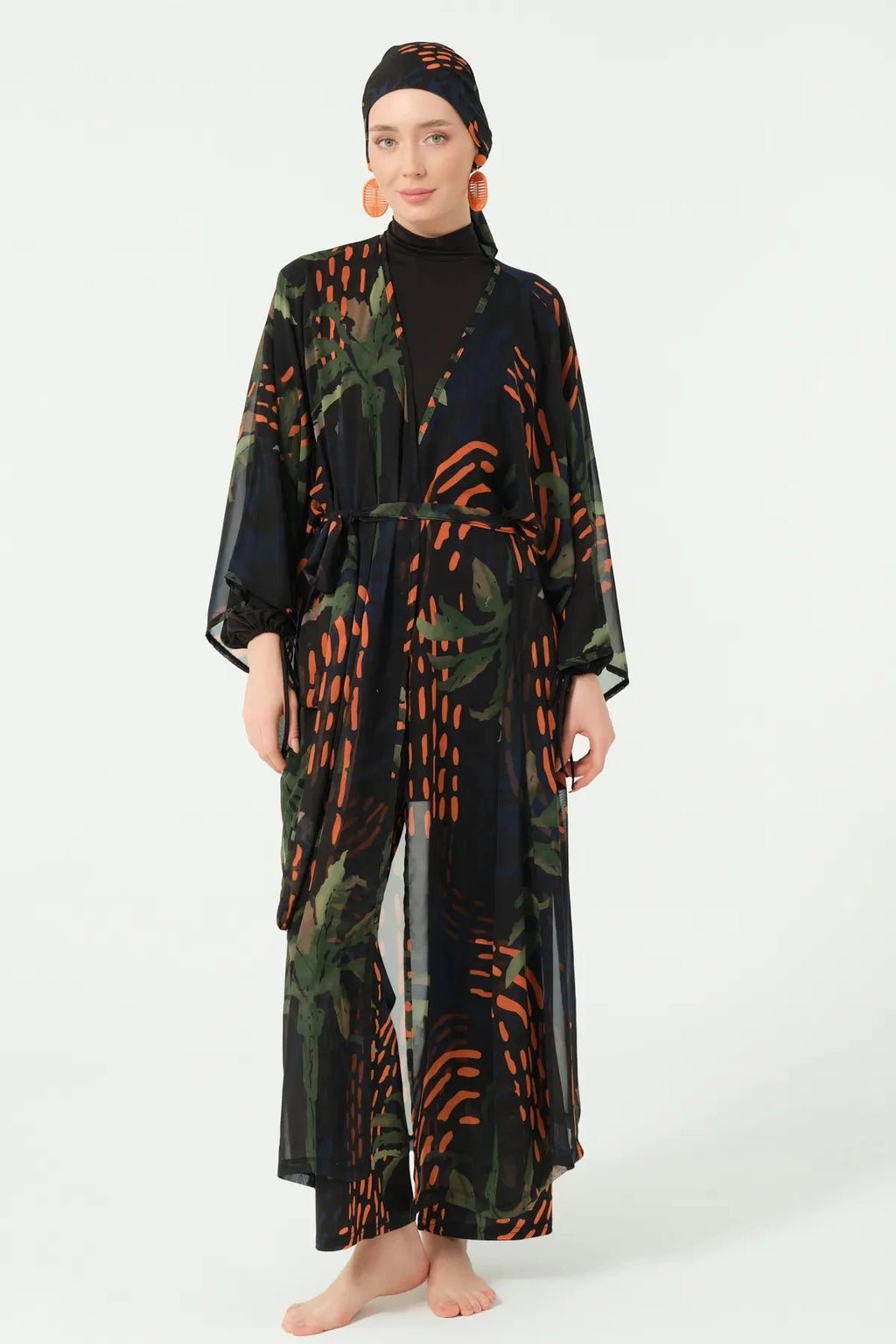 Woman in dark patterned kimono, tied with belt over black modest swimsuit.