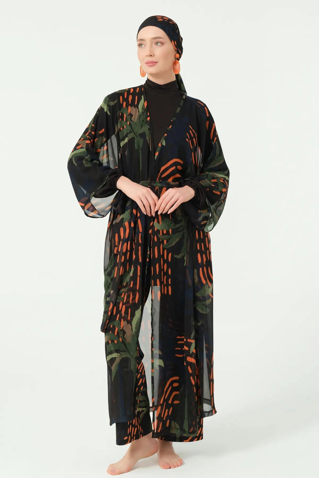 Woman wearing a long, patterned dress with a hood against a white background