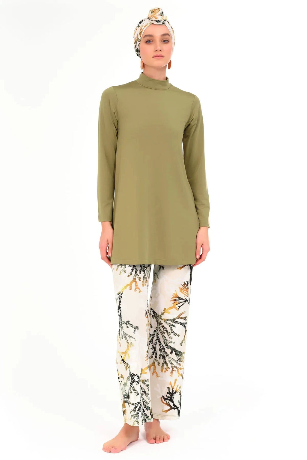 Model in olive green modest swimsuit tunic, printed pants, and head covering