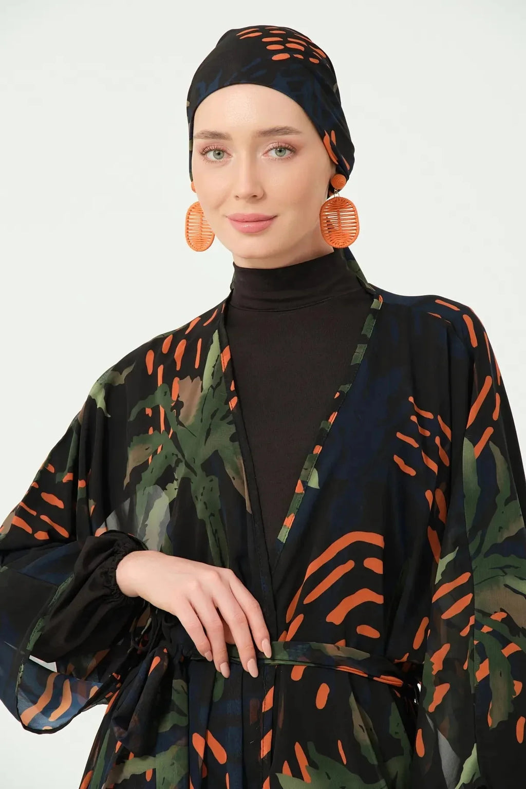 Woman wearing a black and orange patterned outfit with a plain background