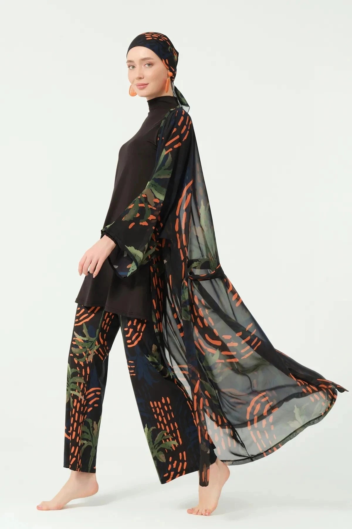 Woman in black modest swimwear with open tropical print kimono, side view.