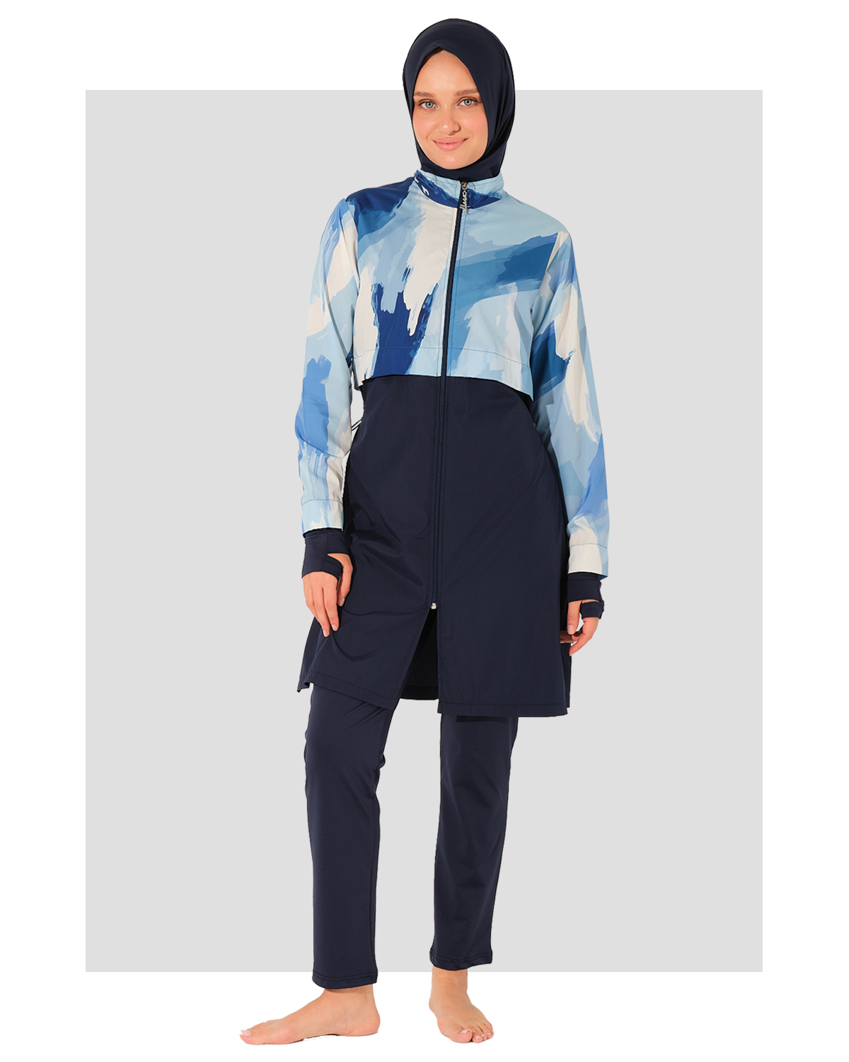 Person wearing a blue and white patterned top with navy pants burkini on a light gray background